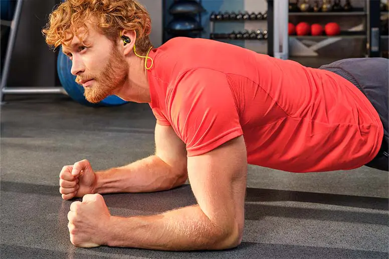 Person nutzt Sport-Kopfhörer Active BT im Fitnessstudio.