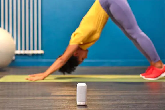 Person beim Yoga, im Vordergrund steht ein Bluetooth-Lautsprecher.