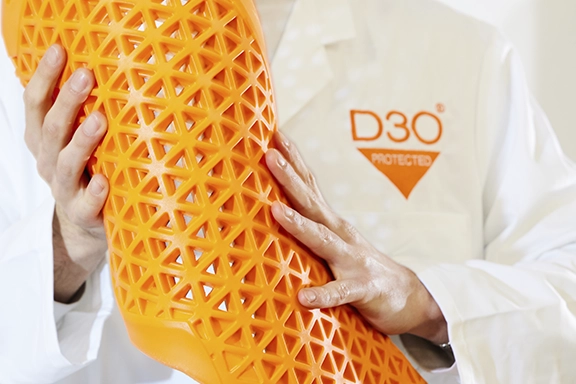 Ein Experte hält eine Matte aus D3O-Material und zeigt die Flexibilität