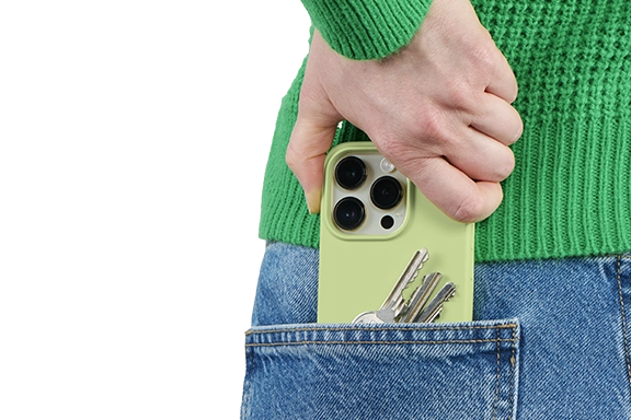 Man sieht die Rückseite einer Frau. Sie trägt blaue Jeans und einen Grünen Strick-Pullover. Sie steckt ihr Smartphone und Schlüssel in die Gesäßtasche.