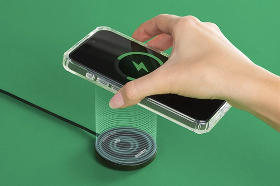 Eine Hand hält ein Smartphone, das in einem MagCase-Cover von Hama steckt, über das induktive Ladegerät von Hama