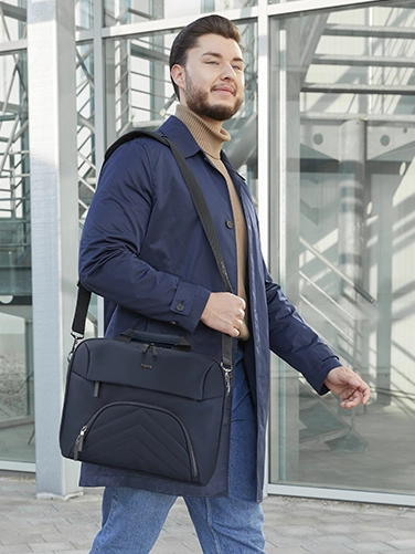 Geschäftsmann trägt die Hama Laptop-Tasche "Premium Lightweight" über der Schulter auf dem Weg zum nächsten Meeting