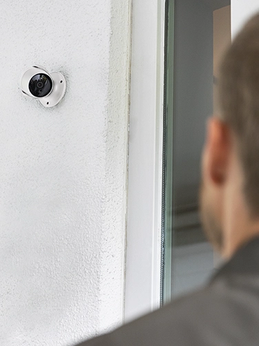 Ein Mann steht vor einer Haustür und wird von der Hama Überwachungskamera gefilmt